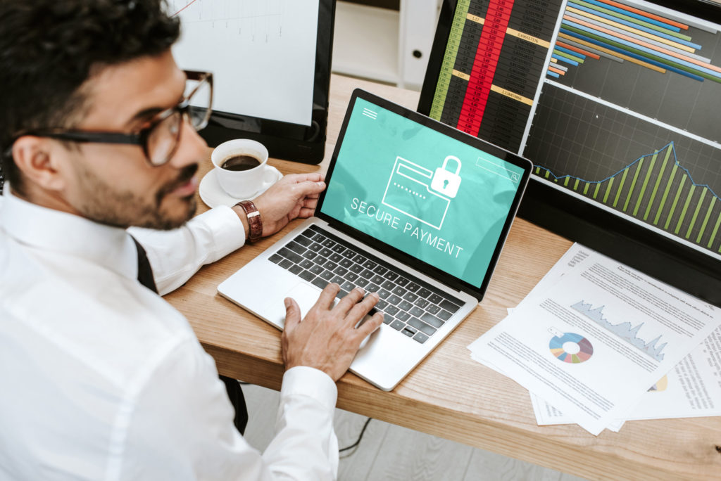 selective focus of bi-racial trader using laptop with secure payment letters